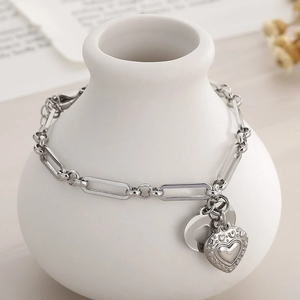 Detail of silver paperclip bracelet with relief heart pendant on ceramic decor