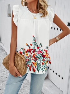 Detail view of white sleeveless top featuring vibrant floral print and ruffled armhole edges