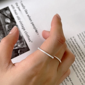 Minimalist S925 sterling silver striped open ring shown on a finger with a magazine backdrop
