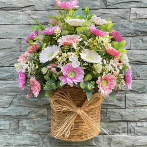 Pastel daisy and eucalyptus arrangement in a rustic woven basket with a natural bow
