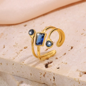 Detail of golden double ring featuring rectangular and round blue sapphires on stone