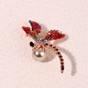 Luxurious dragonfly brooch with colorful rhinestones and champagne pearl on textured stone