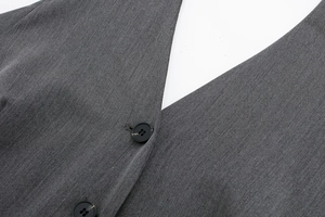 Vue macro d'un gilet gris foncé avec col en V et boutons noirs sur tissu à armure toile