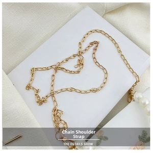 Detail of gold chain strap with lobster clasp and white pearls on lace fabric bag