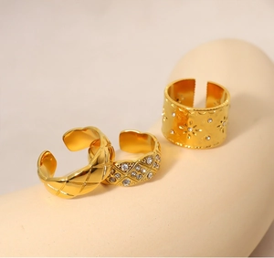 Dettaglio di tre anelli dorati vintage con design traforato e cristalli brillanti incastonati