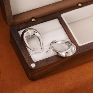 Sleek silver metal U-shaped drop earrings presented in a wooden jewelry box