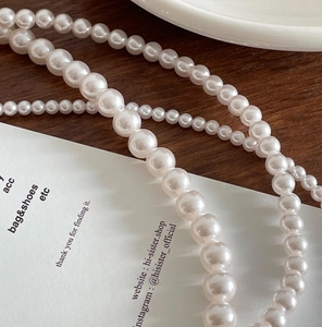 Macro detail of elegant white pearl necklace on a minimalist wooden background