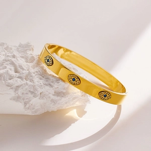 Detailed macro view of gold-plated open bangle with blue evil eye zircon accents