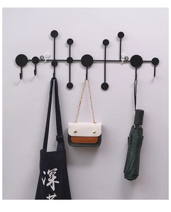 Detail of a black geometric wall-mounted coat rack featuring multiple metal hooks