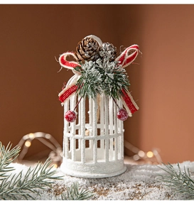 Detailed view of a white birdcage Christmas ornament with pine cones and red berries