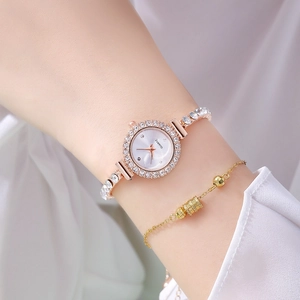 Detailed close-up of a gold quartz watch with a silver diamond-encrusted bracelet on a wrist