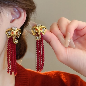 Detailansicht goldener Elefanten-Ohrstecker mit roten Perlenfransen und Perlenakzenten