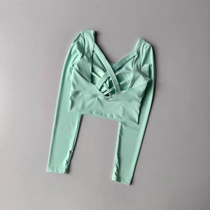 Détail du haut de sport vert menthe avec dos nu croisé sur un fond gris neutre