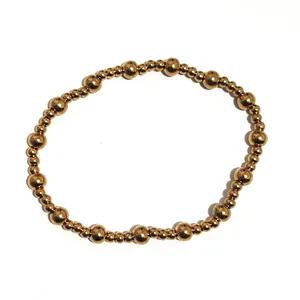 Detalle de cuentas grandes y pequeñas de oro de 18K alternadas en una pulsera elástica