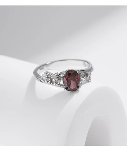 Macro view of vintage silver ring featuring a dark red oval stone and carved floral patterns