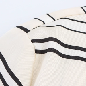 Detail shot of beige satin shirt shoulder seams and black striped fabric texture