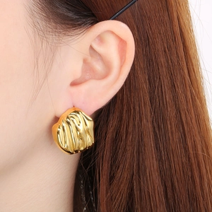 Detail of gold irregular lava texture stainless steel stud earring on ear model