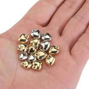 Polished gold and silver heart-shaped CCB pendants displayed on a palm for DIY jewelry