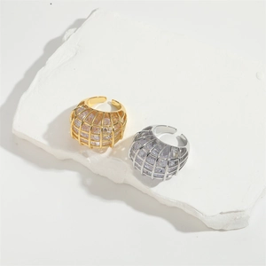 Elegant gold and silver cage rings with sparkling zircon stones on a white stone base