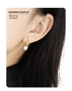 Detailed view of pearl and teardrop crystal drop earrings on model's ear with gold accents