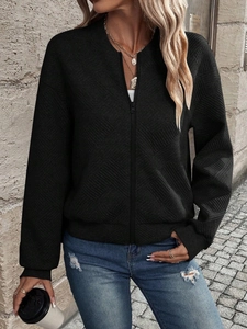 Detailed view of women's black zip-up jacket with textured diamond geometric pattern
