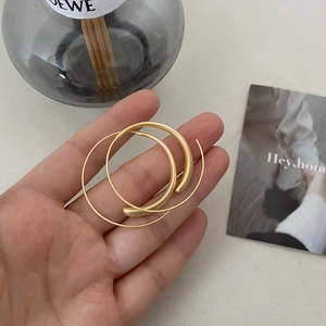 Minimalist matte gold hoop earrings with textured finish shown in a stylish hand-held shot