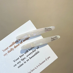 Set of two white pearlescent acetate hair clips for women on an elegant background