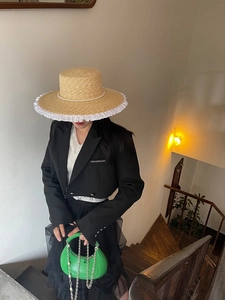 Straw sun hat with white lace trim and pearl detailing for elegant summer beach travel