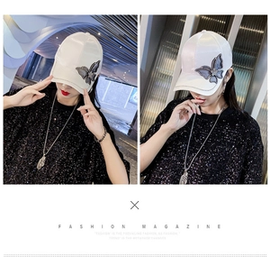 Detail of white satin baseball cap with grey butterfly embroidery and rhinestone brim edge