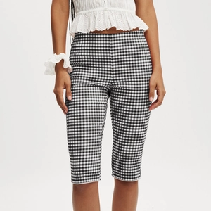 Detail of high waist plaid cropped pants with white lace trim and slim fit design
