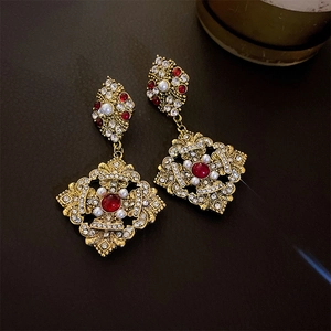 Detailed macro view of baroque vintage gold earrings with red gems and pearls