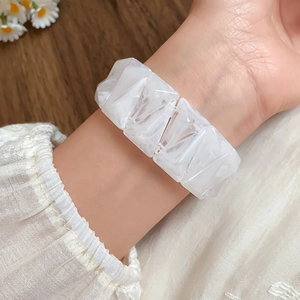 Close-up of white marble pattern acrylic geometric bracelet worn on a woman's wrist