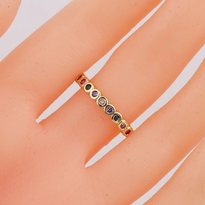 Macro view of gold rainbow ring with multi-colored gemstones on a model hand