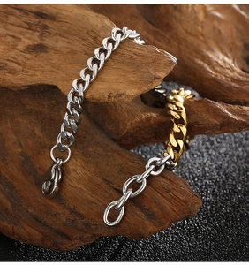 Detail of silver and gold Cuban link chain bracelet on natural wood background