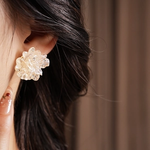 Gros plan d'une boucle d'oreille fleur en nacre avec cristaux portée par un mannequin