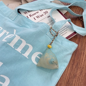 Detail of a blue marble patterned triangular charm hanging on a light blue canvas tote bag