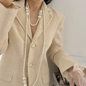 Detail of layered pearl necklace with diamond-encrusted balls on tweed jacket