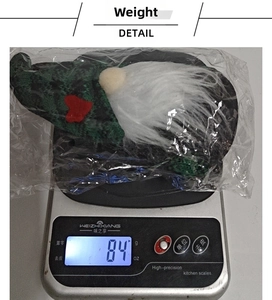 Peso di uno gnomo di Natale verde su una bilancia digitale di 84 grammi