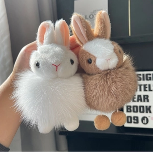 Close-up of plush bunny pendants in white and brown with fluffy faux fur and long ears