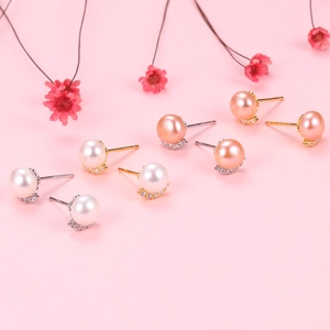 Detailed view of S925 silver pearl earrings with rainbow zircons on pink background