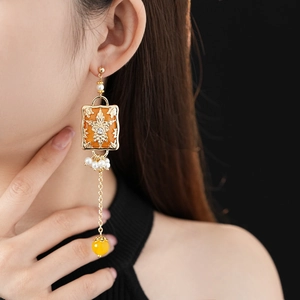 Close-up of vintage gold rectangular earrings with white pearls and flower tassel details