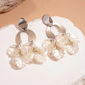 Sparkling acrylic petal tassel earrings with diamond accents on a textured stone stand