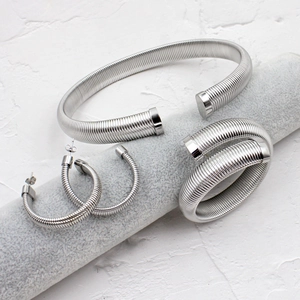 Détail d'un ensemble de bijoux argentés avec design torsadé sur un support gris chic