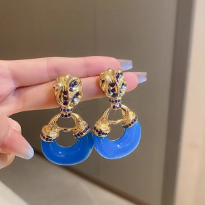 Macro shot of vintage gold earrings with navy blue crescent accents and small blue gems