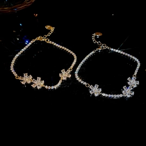 Detailed view of zircon flower bracelets in gold and silver with adjustable extender chains