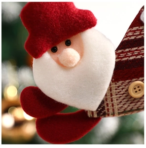 Close-up of handmade Santa Claus plush pendant with wood button and festive background