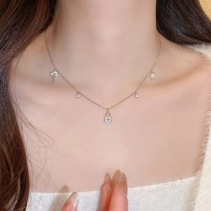 Detail of silver necklace on model featuring key, lock, and pearl charms for women