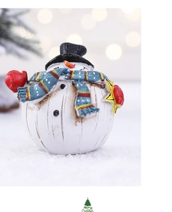 Detail of cute resin snowman figurine with striped scarf and star on snowy surface