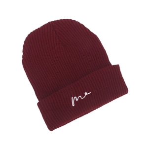 Detailed close-up of dark red ribbed knit beanie with white 'me' script embroidery