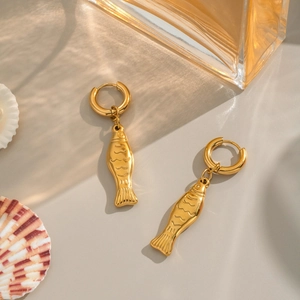 Elegant gold fish earrings set displayed with aesthetic perfume bottle and sea shell